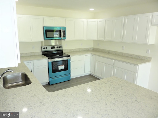 kitchen with stainless steel appliances, wood-type flooring, white cabinets, light stone counters, and sink