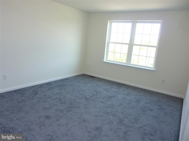 spare room featuring dark carpet