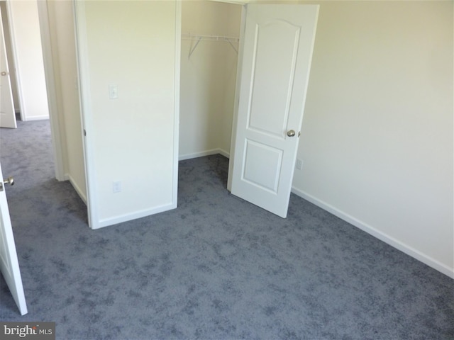 unfurnished bedroom featuring dark colored carpet and a closet