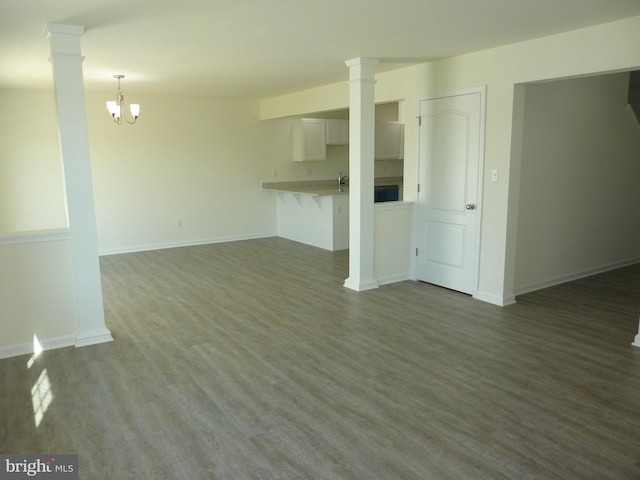 interior space featuring a notable chandelier, dark wood-type flooring, and ornate columns