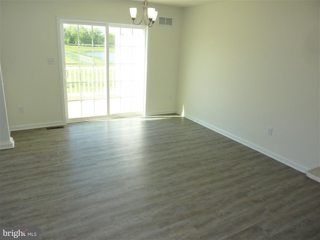 spare room with a notable chandelier and dark hardwood / wood-style flooring