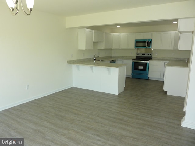 kitchen with an inviting chandelier, appliances with stainless steel finishes, sink, white cabinets, and dark hardwood / wood-style flooring