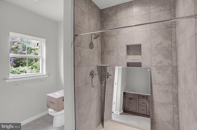 bathroom featuring toilet, a tile shower, and tile flooring