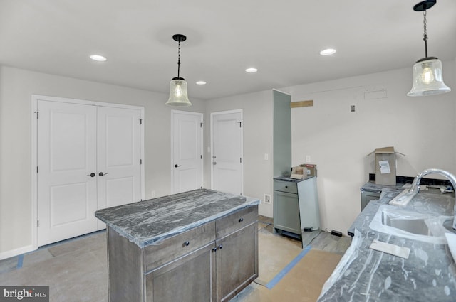 kitchen featuring a kitchen island, sink, pendant lighting, and dark stone countertops