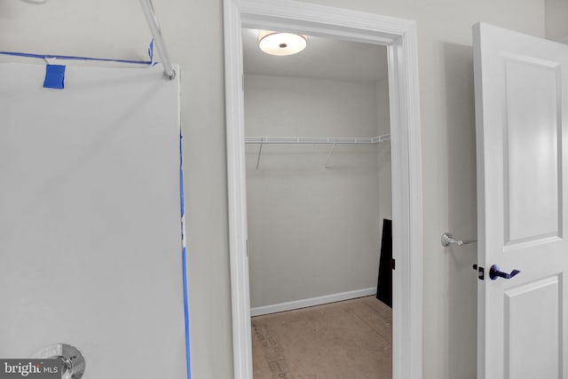 walk in closet with light tile floors