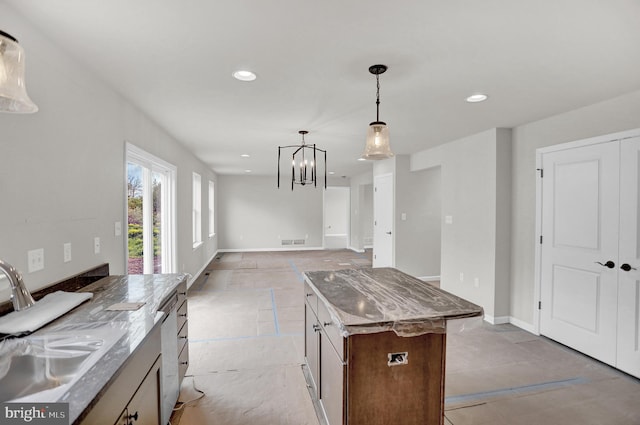 kitchen with pendant lighting, a kitchen island, a notable chandelier, light tile floors, and stone counters