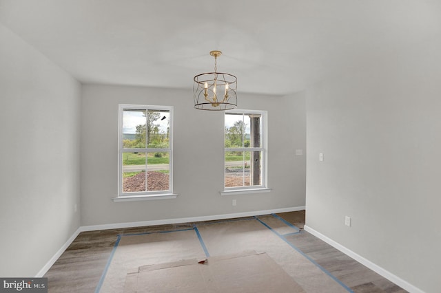 empty room with dark hardwood / wood-style flooring and an inviting chandelier