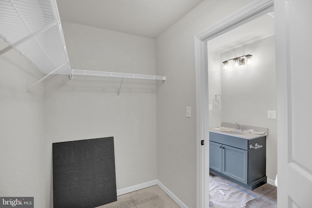 walk in closet featuring sink and light tile floors