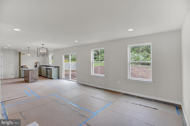 unfurnished living room featuring sink, a chandelier, and a healthy amount of sunlight