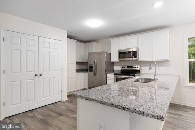 kitchen with sink, appliances with stainless steel finishes, white cabinetry, and light hardwood / wood-style flooring