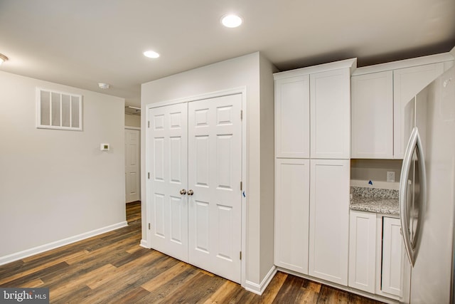 kitchen with white cabinetry, dark hardwood / wood-style flooring, stainless steel fridge, and light stone countertops