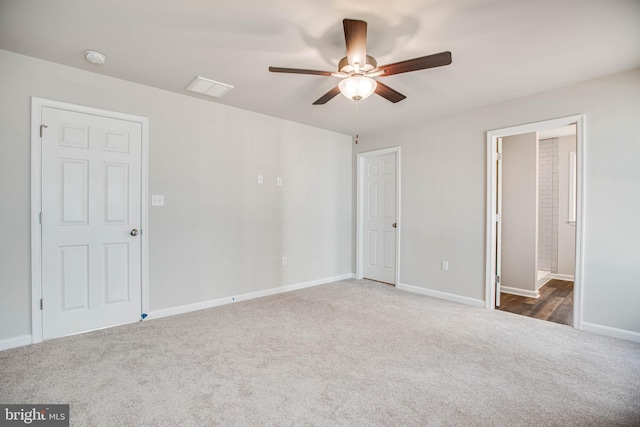 unfurnished bedroom featuring ensuite bath, ceiling fan, and dark carpet