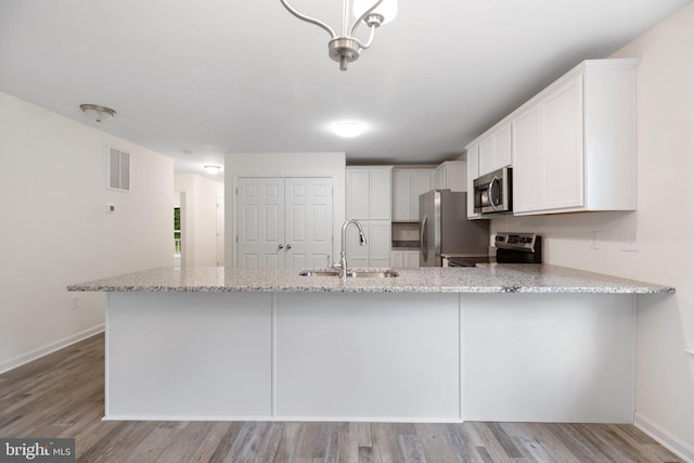 kitchen featuring appliances with stainless steel finishes, sink, light wood-type flooring, and white cabinets