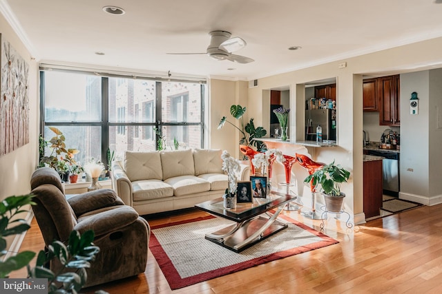 living room with ornamental molding, ceiling fan, and light wood-type flooring