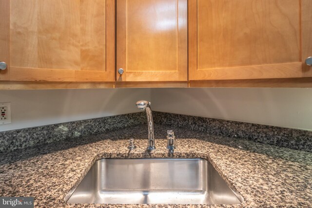 room details featuring dark stone counters and a sink