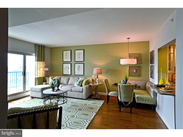 living area featuring baseboards, a textured ceiling, and wood finished floors