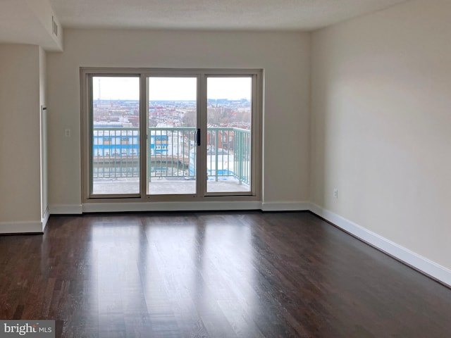 spare room featuring baseboards and dark wood-type flooring