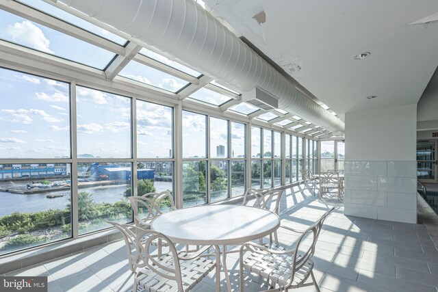 sunroom featuring a water view