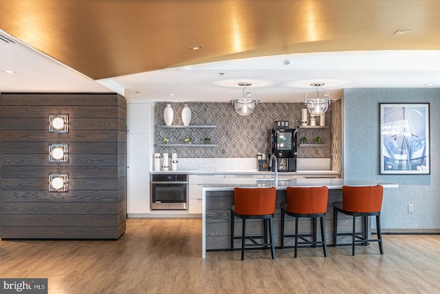 kitchen featuring a kitchen bar, light countertops, light wood-style floors, and oven