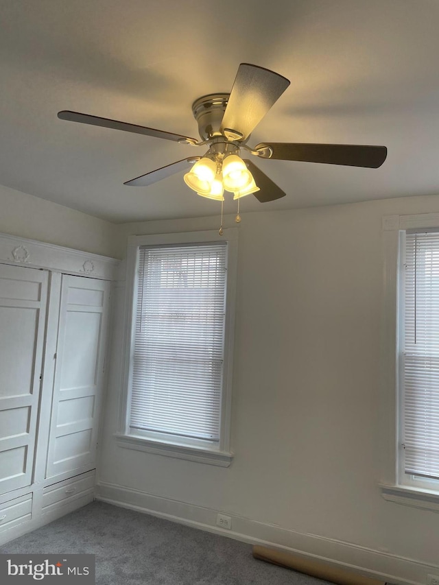 interior space with dark carpet, a closet, and ceiling fan