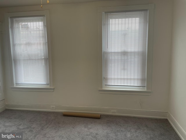 spare room featuring dark carpet and a wealth of natural light