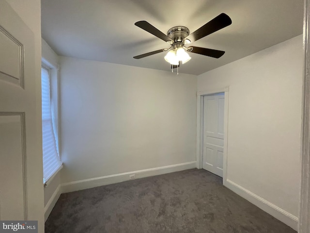 spare room featuring ceiling fan and dark carpet