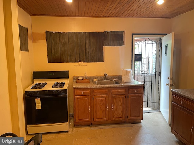 kitchen featuring sink, wood ceiling, white gas range, and light tile flooring