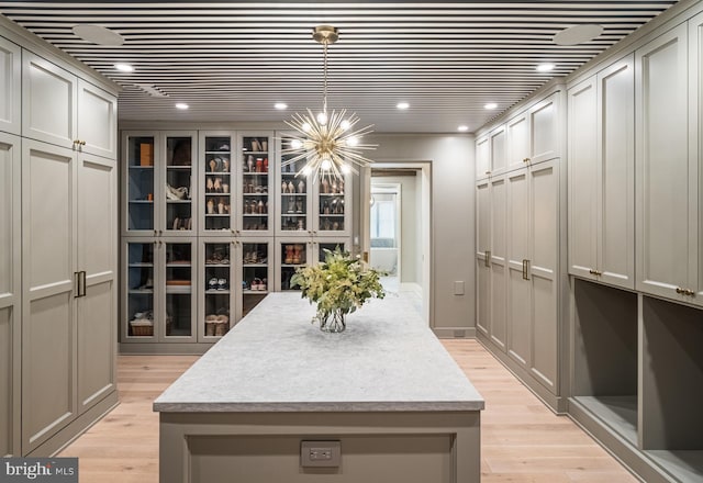 spacious closet with an inviting chandelier and light hardwood / wood-style flooring