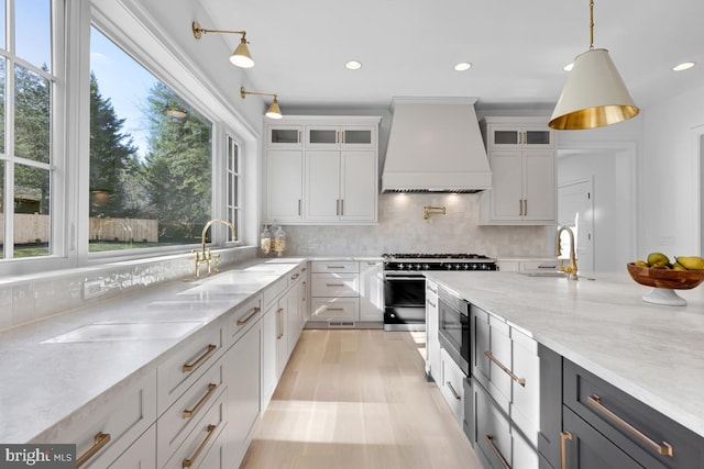 kitchen with pendant lighting, light wood-type flooring, tasteful backsplash, custom exhaust hood, and white cabinets