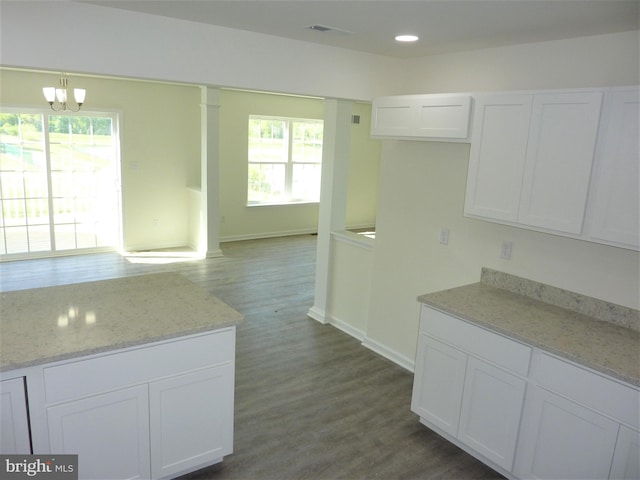 kitchen featuring dark hardwood / wood-style flooring, light stone countertops, a notable chandelier, and white cabinetry