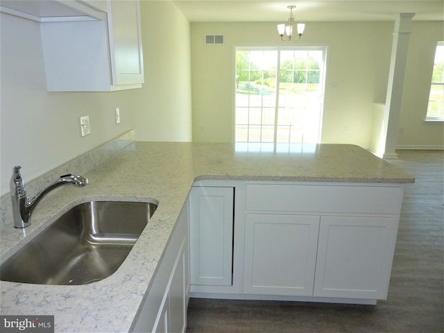 kitchen featuring dark hardwood / wood-style flooring, a notable chandelier, sink, and light stone countertops