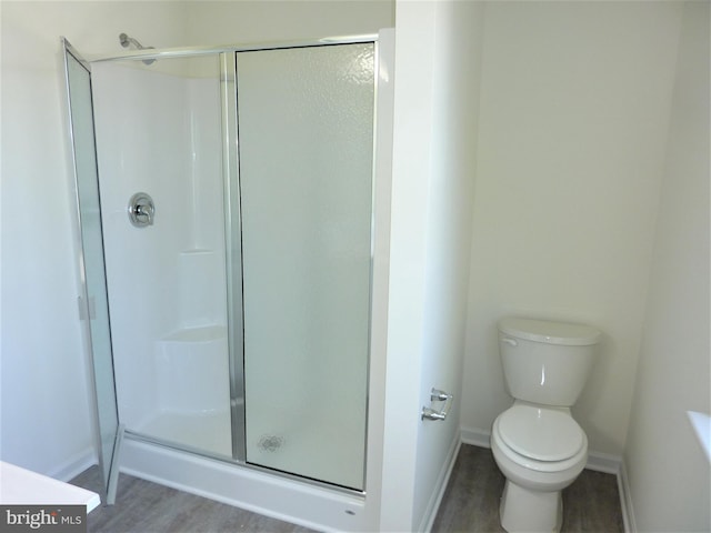 bathroom featuring a shower with shower door, wood-type flooring, and toilet