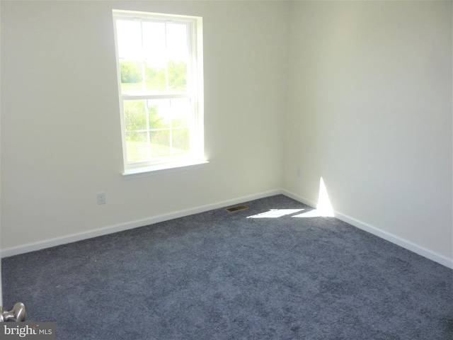 unfurnished room with dark colored carpet and a wealth of natural light