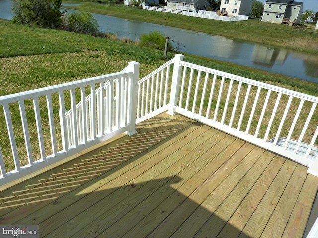 wooden terrace featuring a water view and a yard