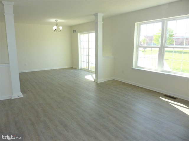 spare room with dark hardwood / wood-style floors, a chandelier, and decorative columns