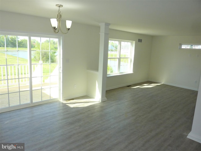 spare room with an inviting chandelier and dark wood-type flooring