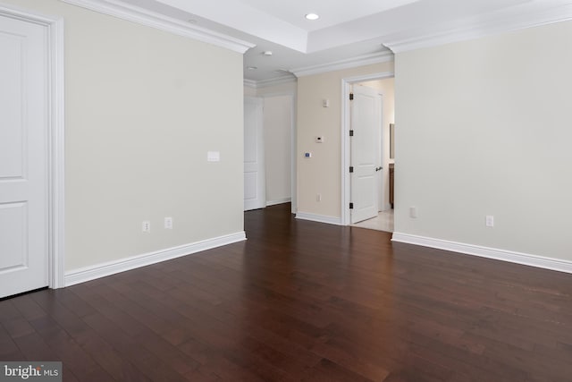 empty room with crown molding, dark hardwood / wood-style floors, and a raised ceiling