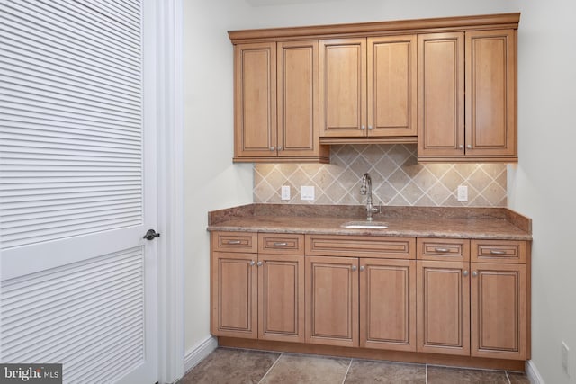 kitchen with sink, backsplash, stone countertops, and light tile floors