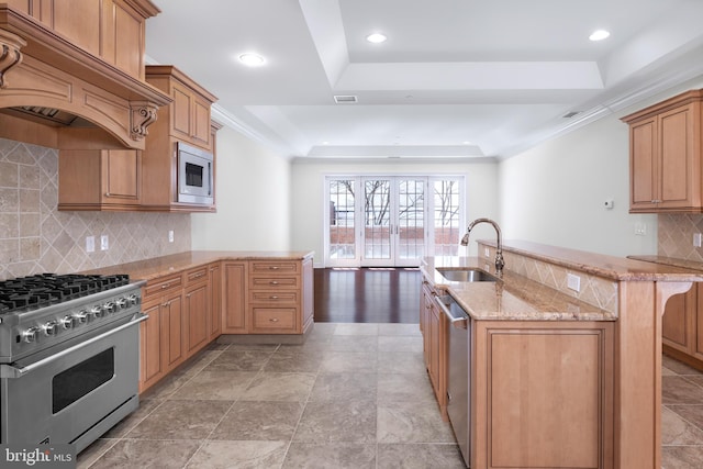 kitchen with backsplash, a tray ceiling, appliances with stainless steel finishes, sink, and custom range hood