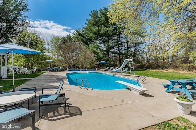 view of pool with a water slide, a patio area, a yard, and a diving board