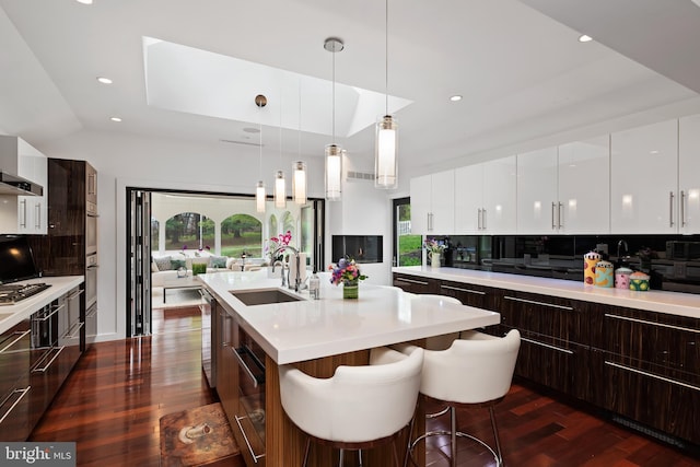 kitchen featuring hanging light fixtures, a breakfast bar area, sink, tasteful backsplash, and dark hardwood / wood-style flooring