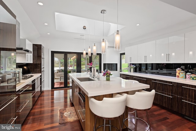 kitchen featuring decorative light fixtures, tasteful backsplash, a breakfast bar area, dark hardwood / wood-style floors, and sink