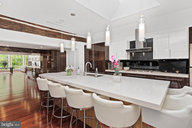 kitchen featuring white cabinetry, dark wood-type flooring, a breakfast bar, sink, and pendant lighting