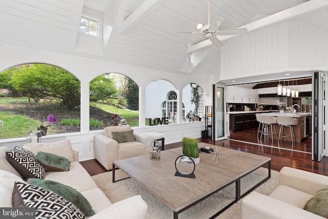 interior space featuring dark hardwood / wood-style flooring, ceiling fan, beam ceiling, and plenty of natural light