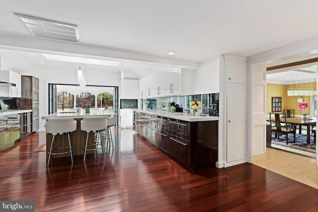 kitchen featuring an island with sink, a kitchen bar, pendant lighting, and hardwood / wood-style floors