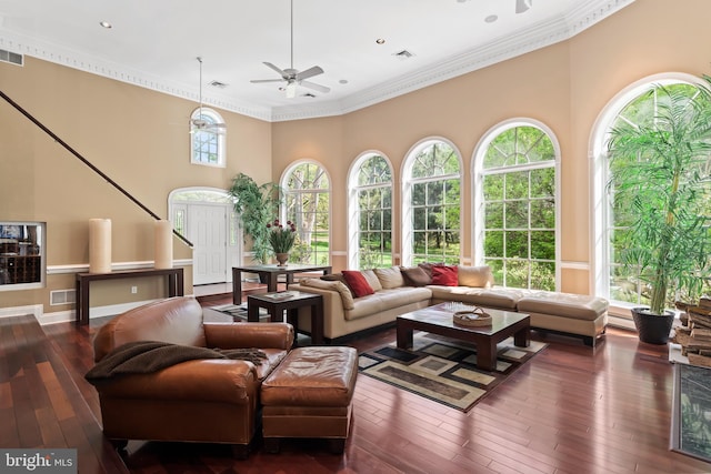 living room with plenty of natural light, crown molding, and dark wood-type flooring