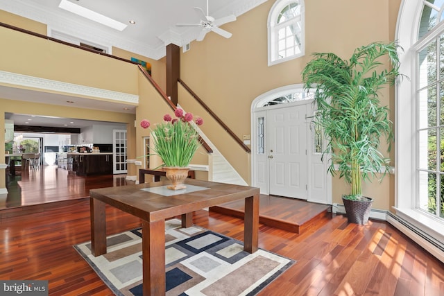 foyer with ornamental molding, ceiling fan, a towering ceiling, and dark hardwood / wood-style flooring