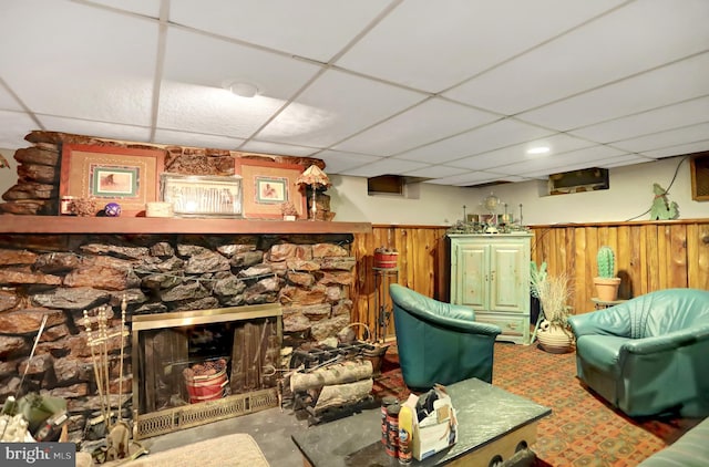 living room with a paneled ceiling, a stone fireplace, and bar