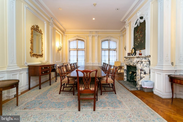 dining area featuring dark parquet flooring, ornamental molding, and decorative columns