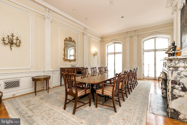 dining room with light parquet flooring, ornamental molding, and decorative columns